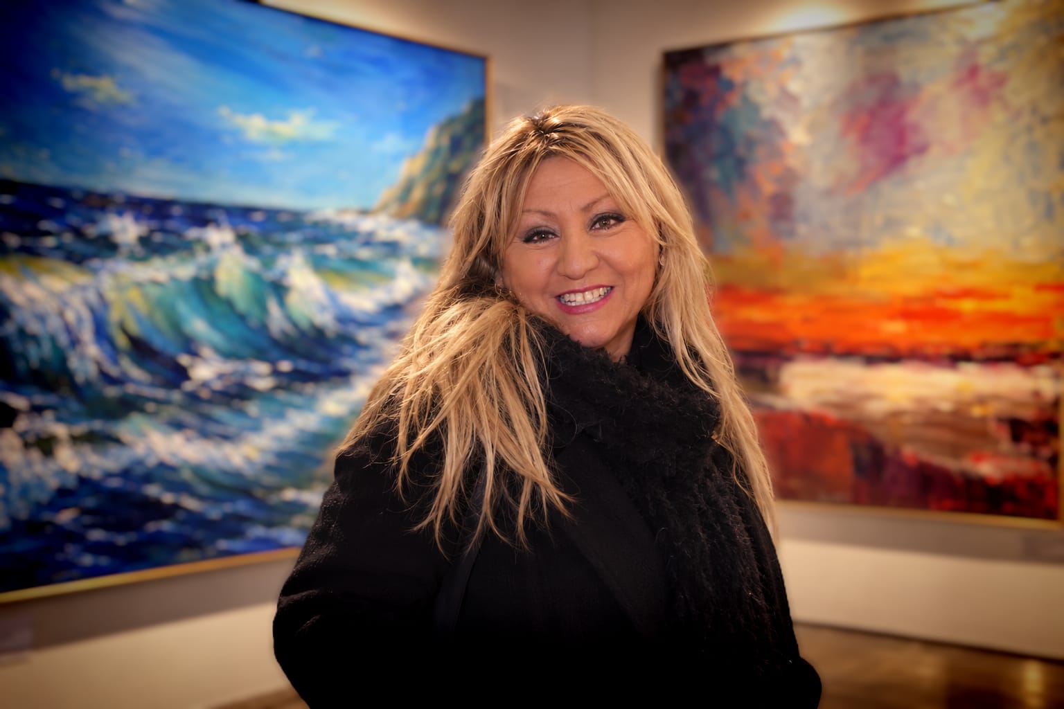 Tamara de las Tormentas en una sala de exposición frente a dos de sus óleos
